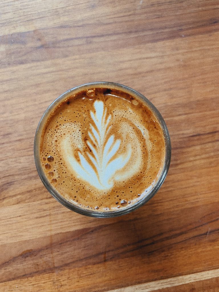 A latte with leaf art on a wooden table