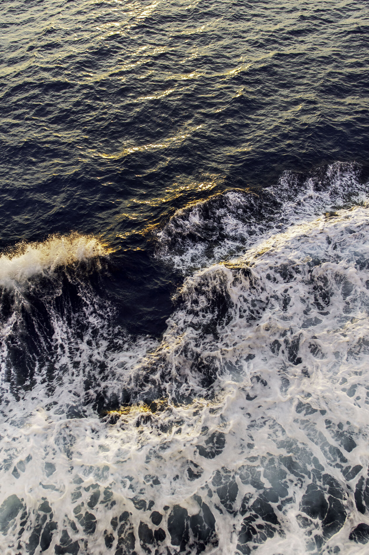 Churning open sea with white foam at sunset