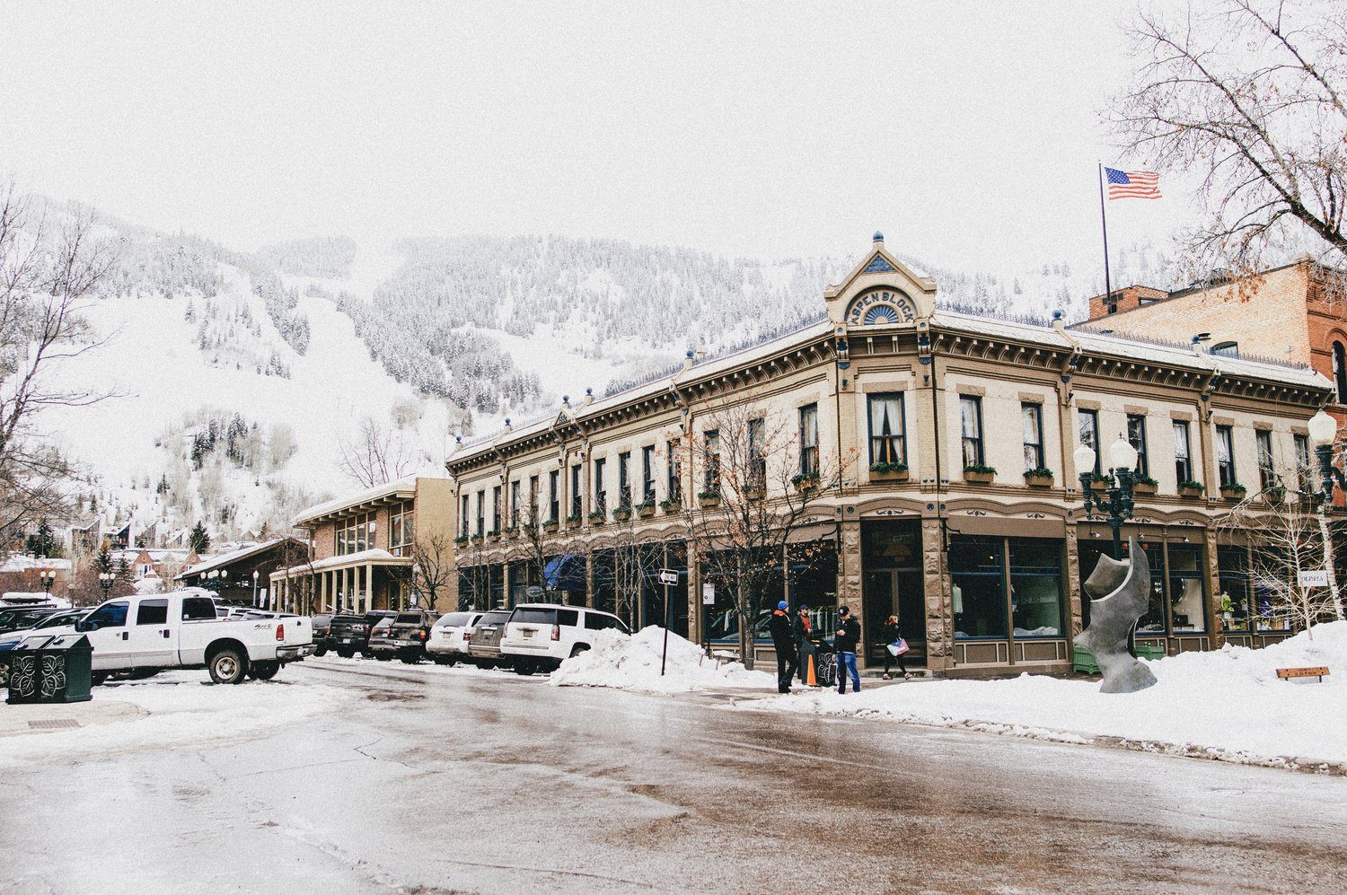 A historic brick building on a snowy street below ski slopes