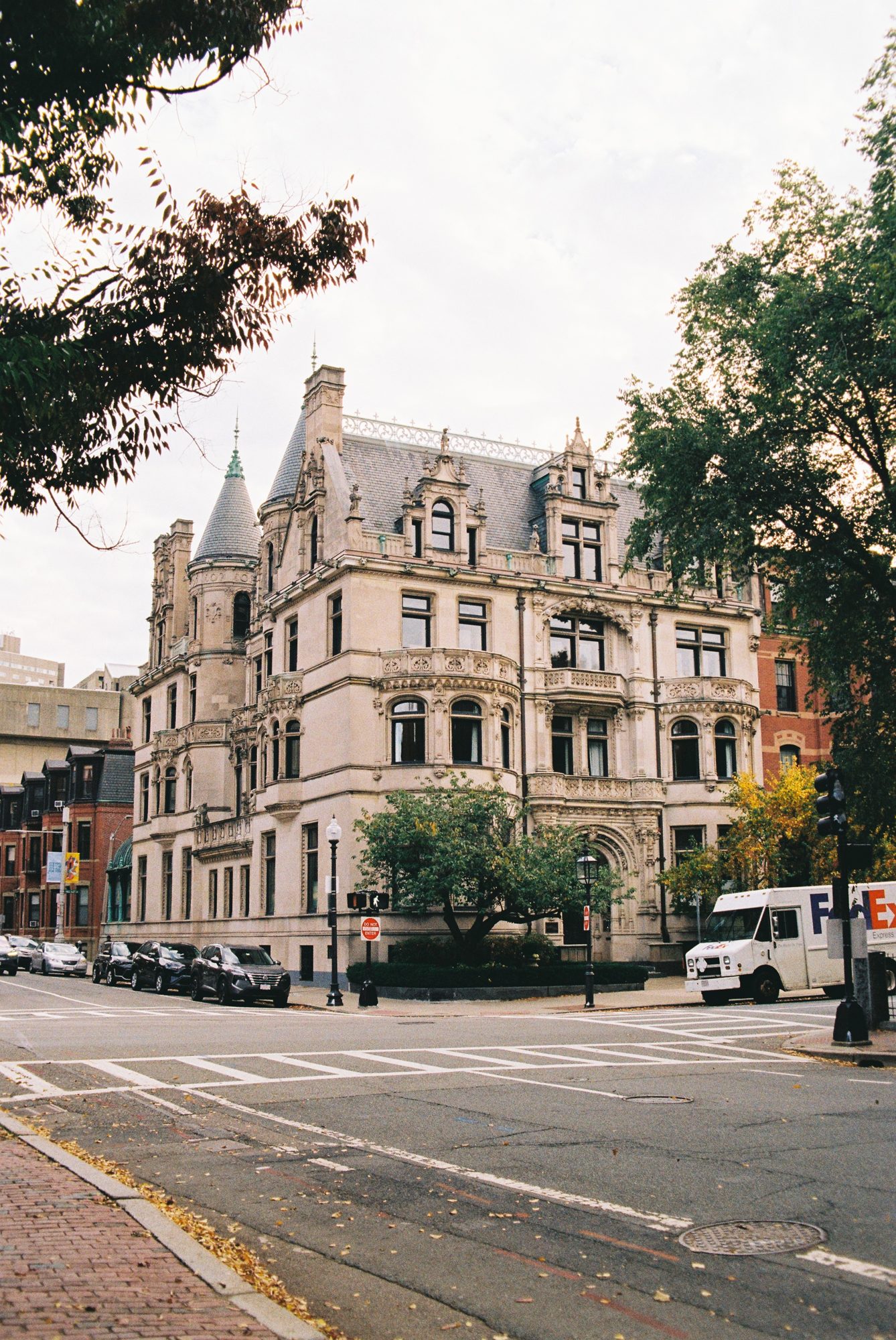An ornate stone building on a tree-lined corner