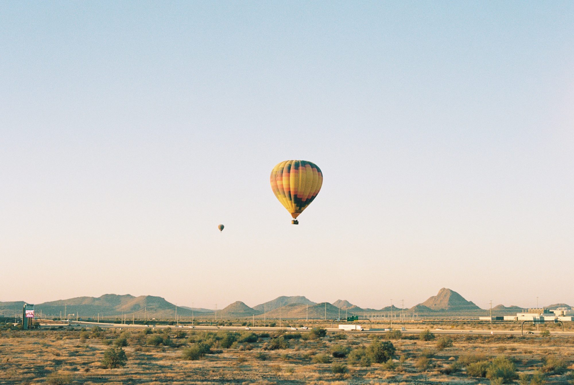 A hot air balloon drifting over a desert plain at dawn