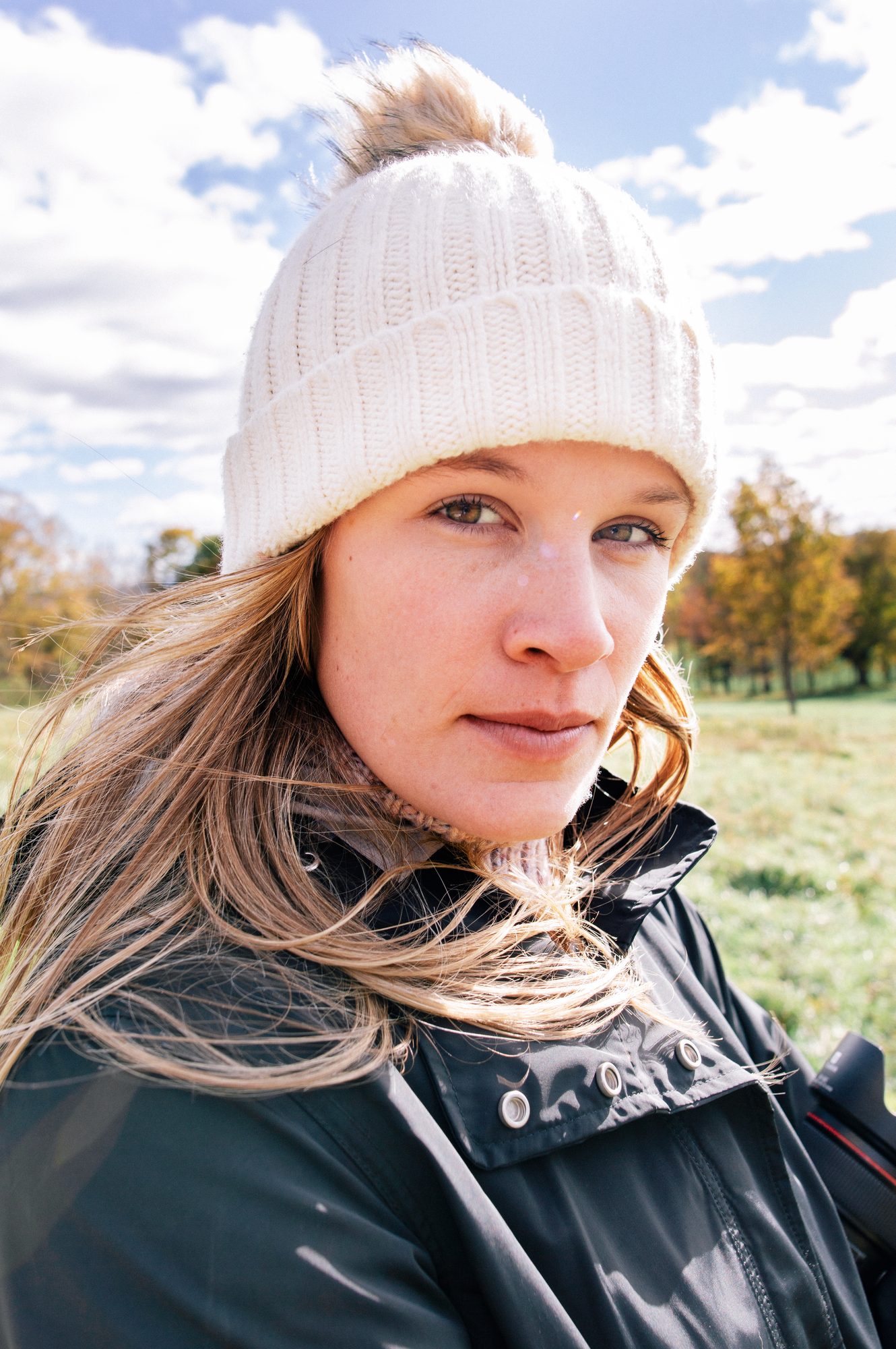 A close portrait of a woman in a white knit hat