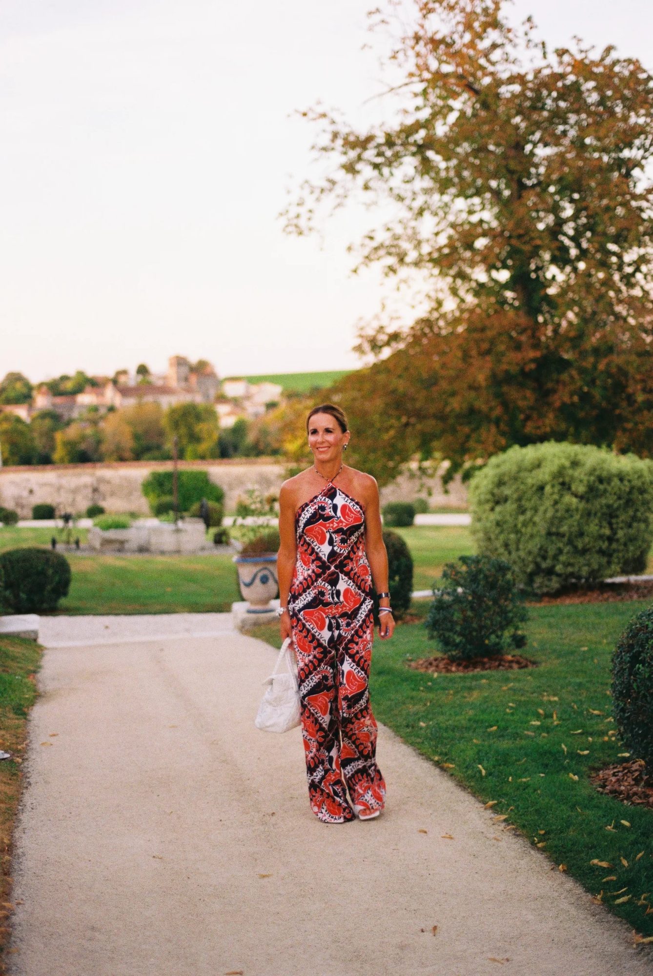 A woman in a patterned dress walking down a garden path