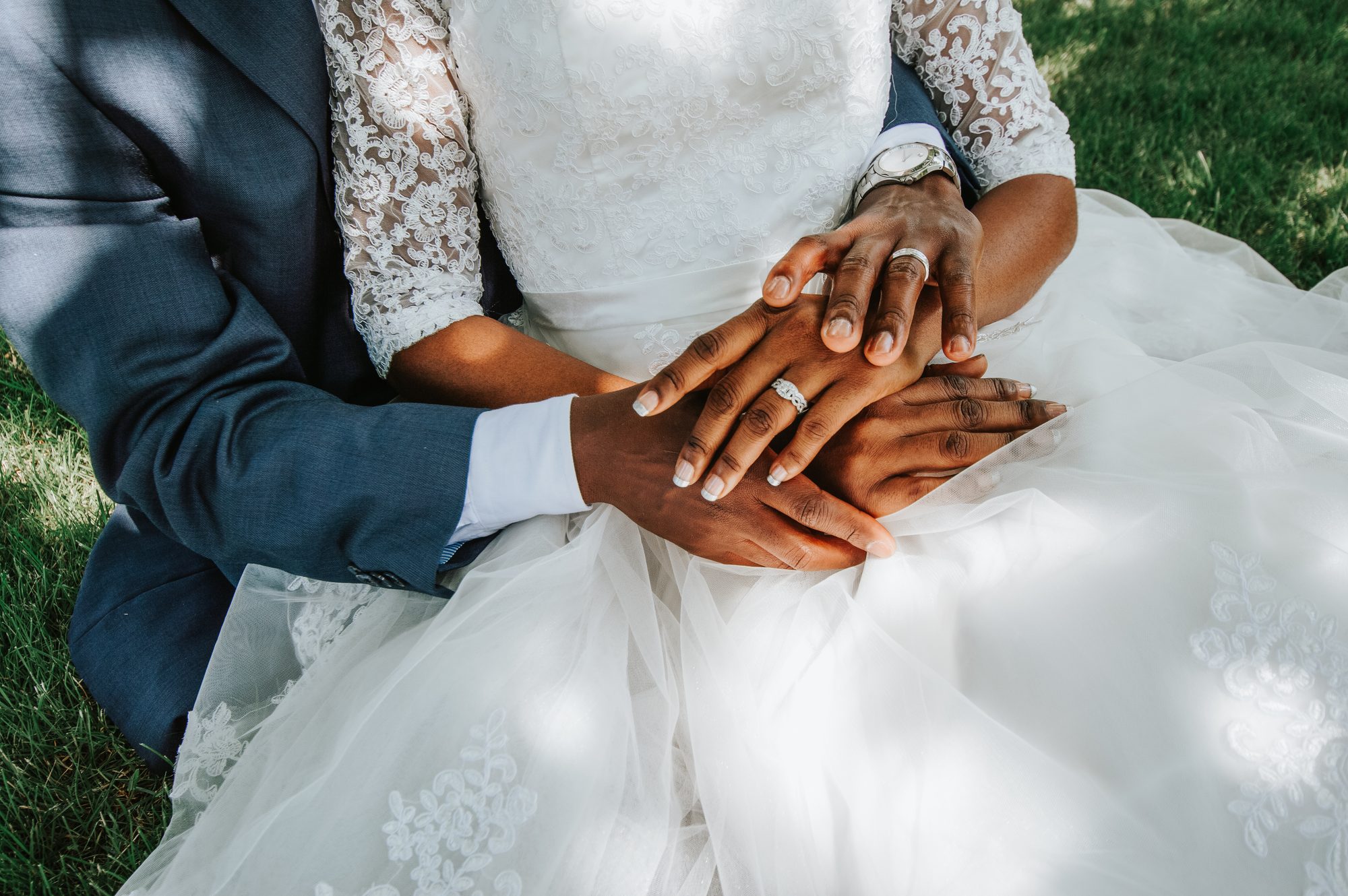 Joined hands resting on a lace wedding dress