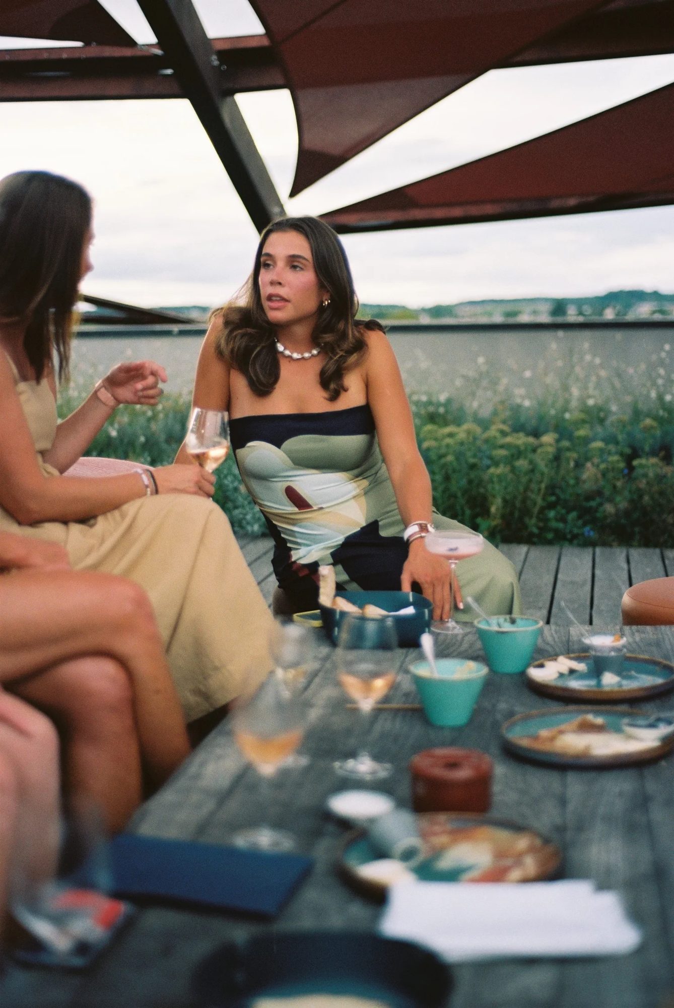 Friends talking around a long outdoor table under a canopy