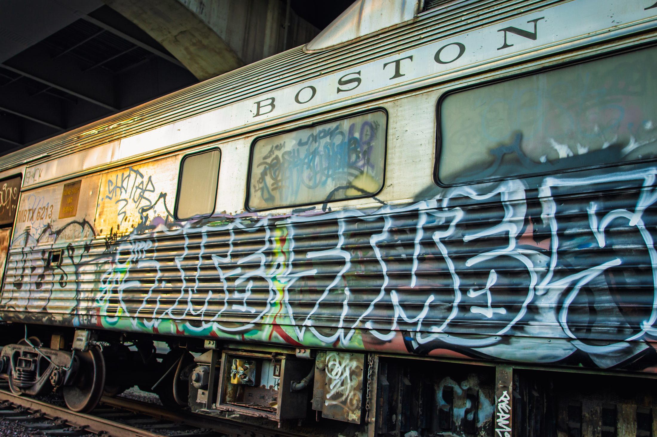 A graffiti-covered passenger car with BOSTON lettered along the top