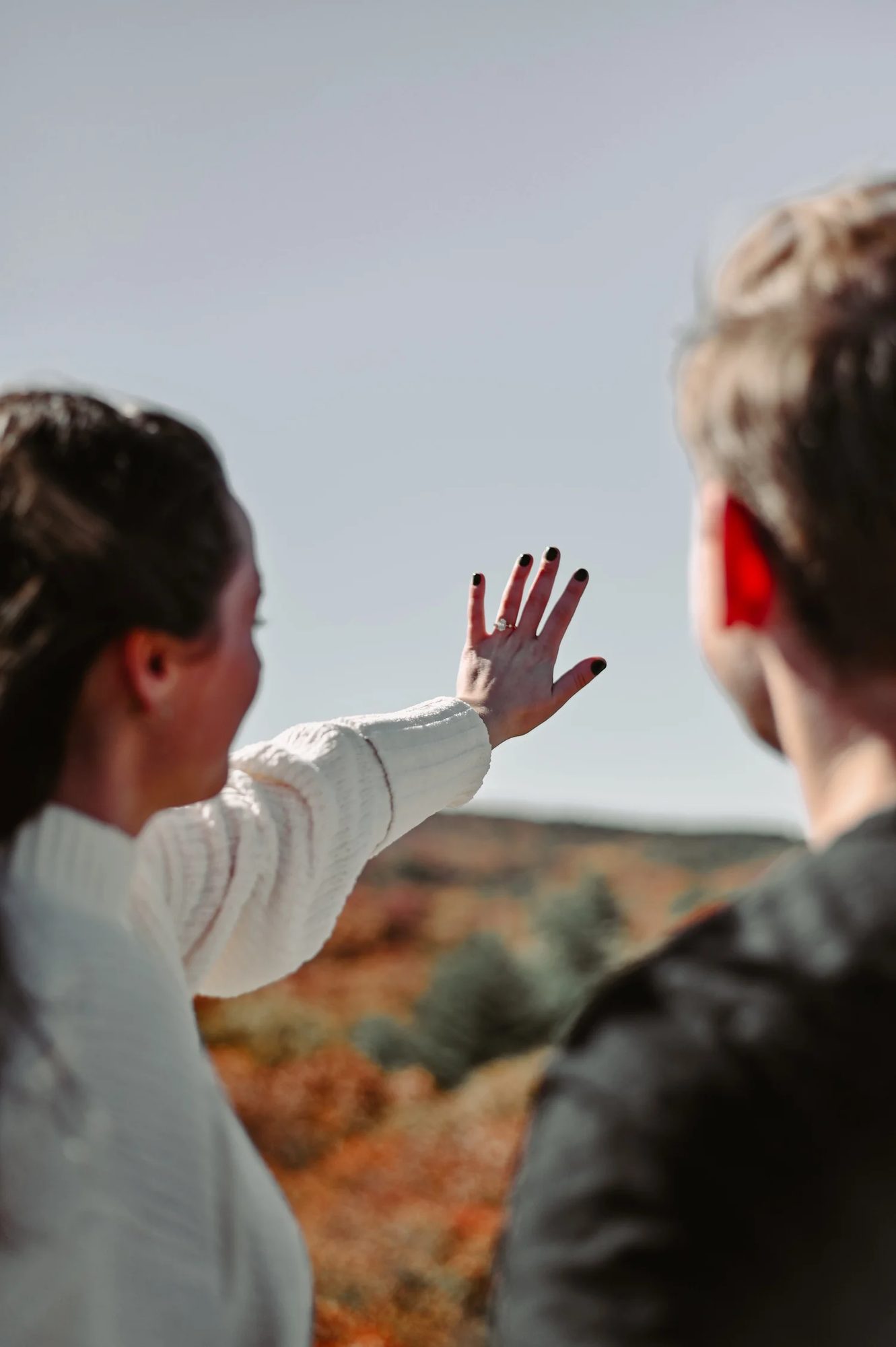 A woman raising her hand toward the sky beside a friend